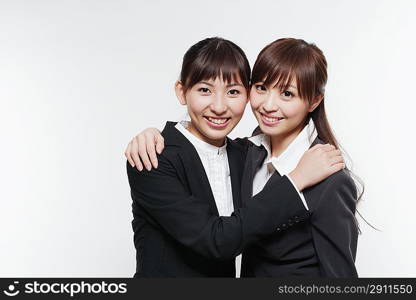 Portrait of two young woman in business suit hugging