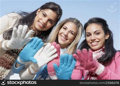 Portrait of two young women and a mid adult woman holding gloves