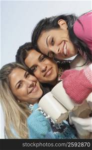 Portrait of two young women and a mid adult woman toasting coffee mugs