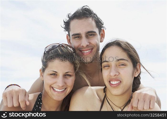 Portrait of two young women and a young man smiling