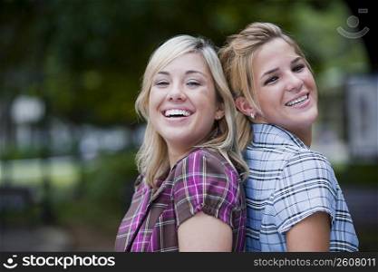 Portrait of two young women back to back and smiling