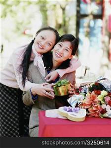 Portrait of two young women holding a gift and smiling