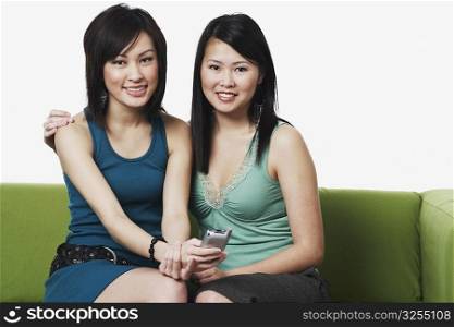 Portrait of two young women holding a mobile phone