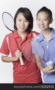 Portrait of two young women holding badminton rackets and smiling