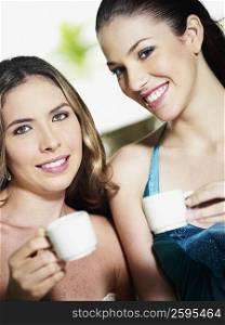 Portrait of two young women holding coffee cups