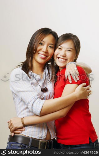 Portrait of two young women hugging each other and looking cheerful