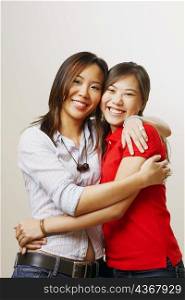 Portrait of two young women hugging each other and looking cheerful