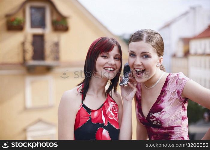 Portrait of two young women listening to a mobile phone