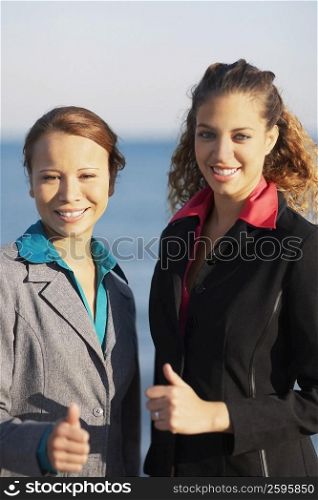Portrait of two young women showing thumbs up signs