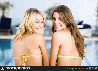 Portrait of two young women sitting at the poolside