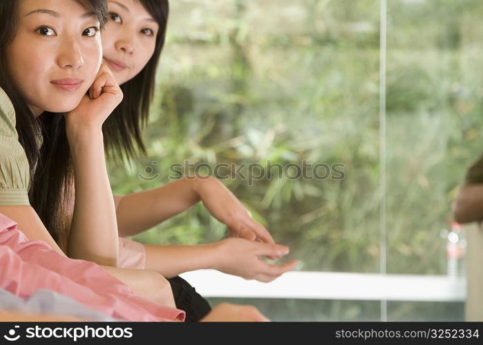 Portrait of two young women sitting side by side