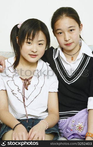 Portrait of two young women sitting together on a couch