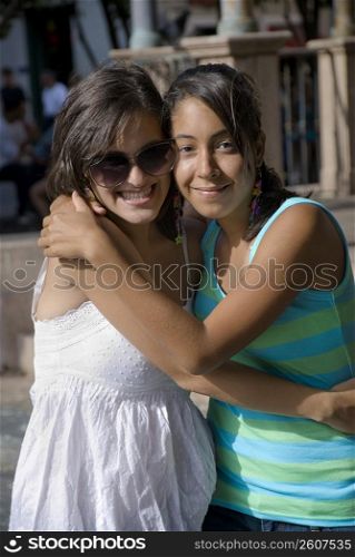 Portrait of two young women smiling and embracing each other