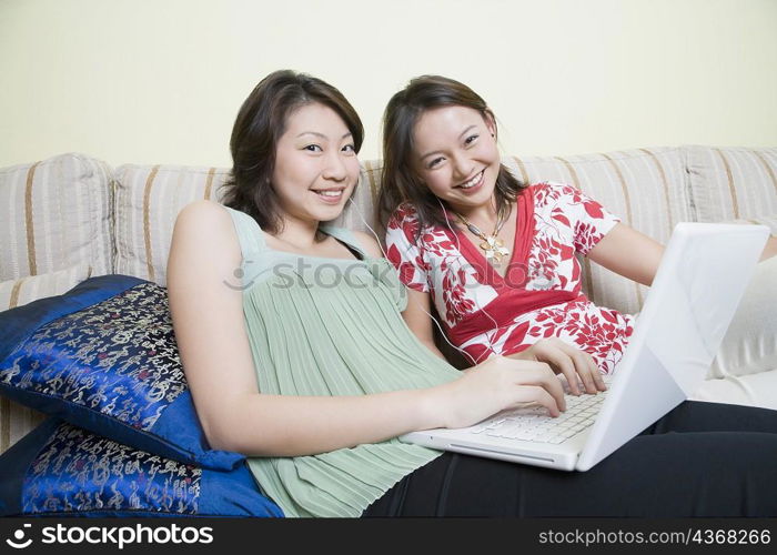 Portrait of two young women smiling and using a laptop