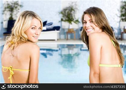 Portrait of two young women smiling at the poolside