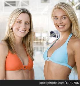 Portrait of two young women standing at the poolside