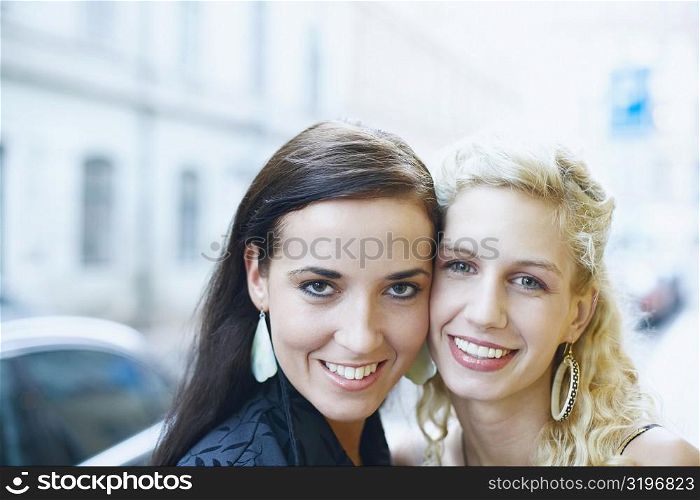 Portrait of two young women standing cheek to cheek
