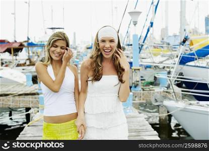 Portrait of two young women standing on a pier and smiling