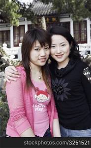 Portrait of two young women standing together smiling