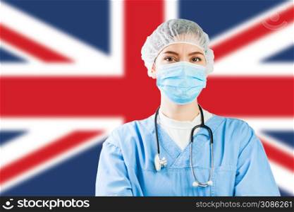 Portrait of UK NHS EMS caucasian hospital frontline ICU GP doctor in PPE Personal Protective Equipment,Great Britain flag background,COVID-19 virus disease crisis,Coronavirus global worldwide pandemic