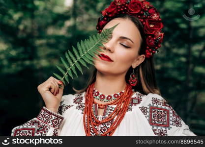 Portrait of ukrainian woman with fern in Carpathian mountains forest. She in in traditional ukrainian wreath, national dress - vyshyvanka, ancient coral beads.. Portrait of ukrainian woman with fern on Carpathian mountains forest background