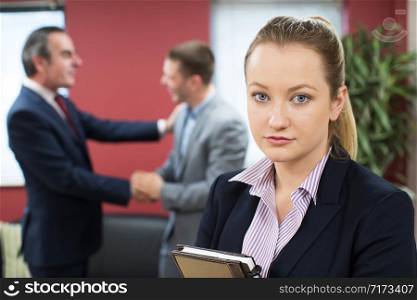 Portrait Of Unhappy Businesswoman With Male Colleague Being Congratulated