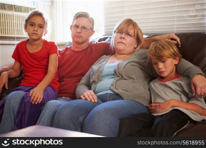 Portrait Of Unhappy Family Sitting On Sofa Together