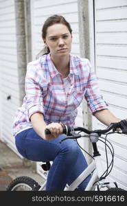 Portrait Of Unhappy Teenage Girl In Urban Setting Riding Bike