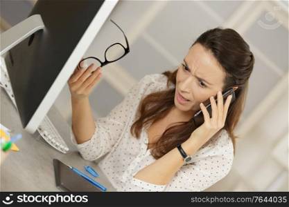 portrait of unhappy young businesswoman speaking on phone in office
