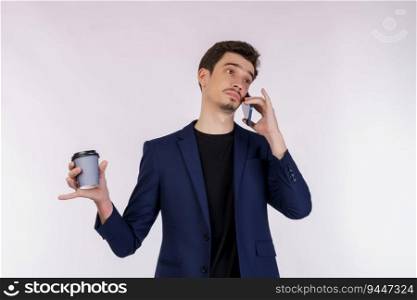 Portrait of unsatisfied handsome businessman talking by mobile phone and holding hot coffee isolated over white background.
