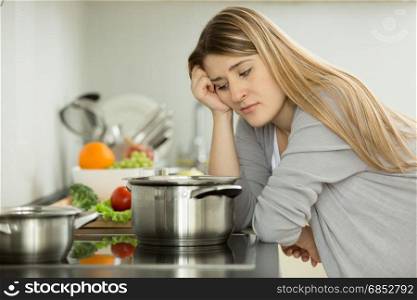 Portrait of upset woman cooking soup on kitchen