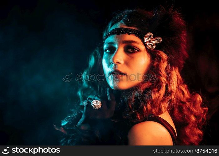 Portrait of vintage styled red haired woman dressed in Great Gatsby era flirting and posing on velours background. Roaring twenties, retro, party, fashion concept. High quality photo. Old-fashioned woman dressed in style of Flappers posing with cigarette in mouthpiece on dark background with neon light. Roaring twenties, retro, party, fashion concept