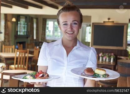 Portrait Of Waitress Serving Food In Restaurant
