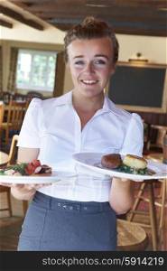 Portrait Of Waitress Serving Food In Restaurant