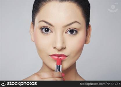 Portrait of woman applying lipstick