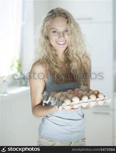 Portrait of woman carrying eggs in kitchen