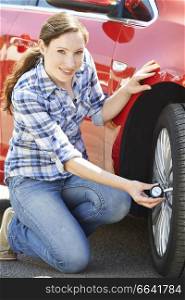 Portrait Of Woman Checking Car Tyre Pressure Using Gauge