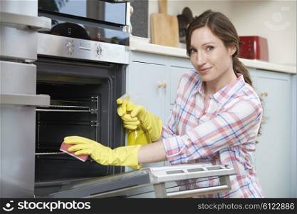 Portrait Of Woman Cleaning Oven At Home