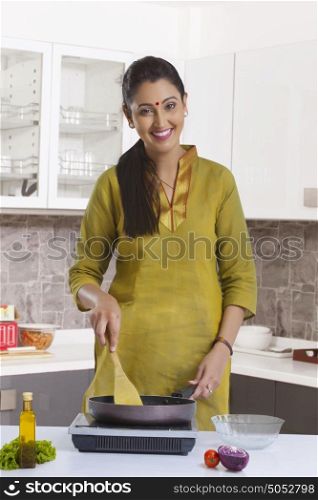 Portrait of woman cooking in kitchen