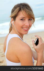 Portrait of woman exercising on the beach with headphones on