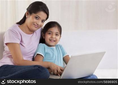 Portrait of woman helping her daughter to use a laptop