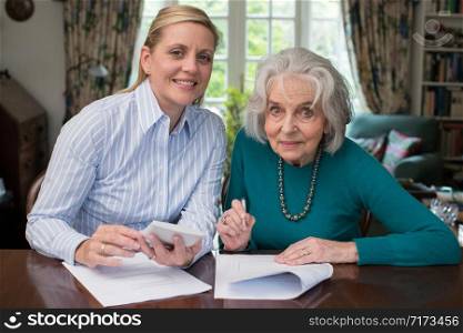 Portrait Of Woman Helping Senior Neighbor With Paperwork