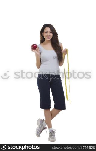 Portrait of woman holding apple and measuring tape