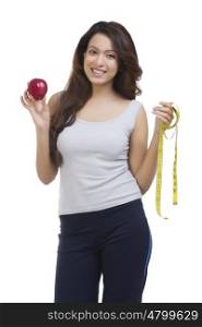 Portrait of woman holding apple and measuring tape