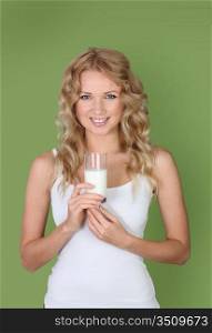 Portrait of woman holding glass of milk on green background