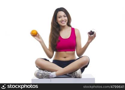 Portrait of woman holding orange and cherries