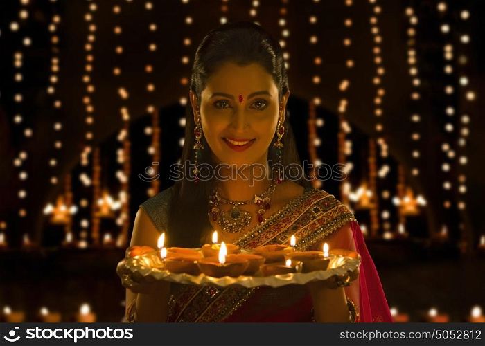 Portrait of woman holding tray of diyas