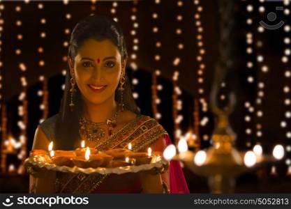 Portrait of woman holding tray of diyas