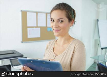 portrait of woman in an office holding a clipboard