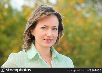 portrait of woman in early fall park. she is looking at camera